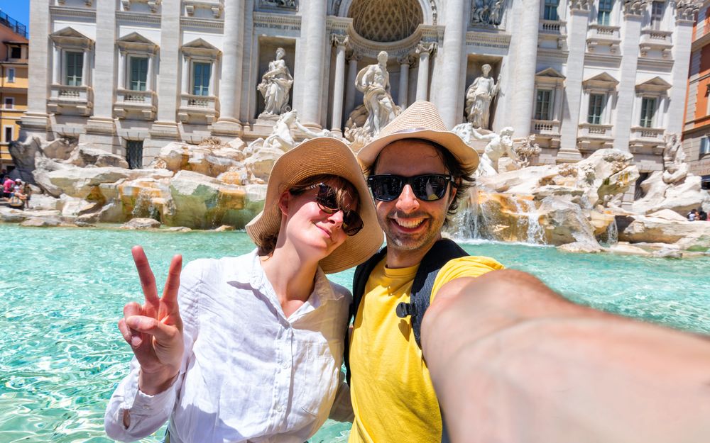 Travelers taking a selfie at the Trevi Fountain in Rome