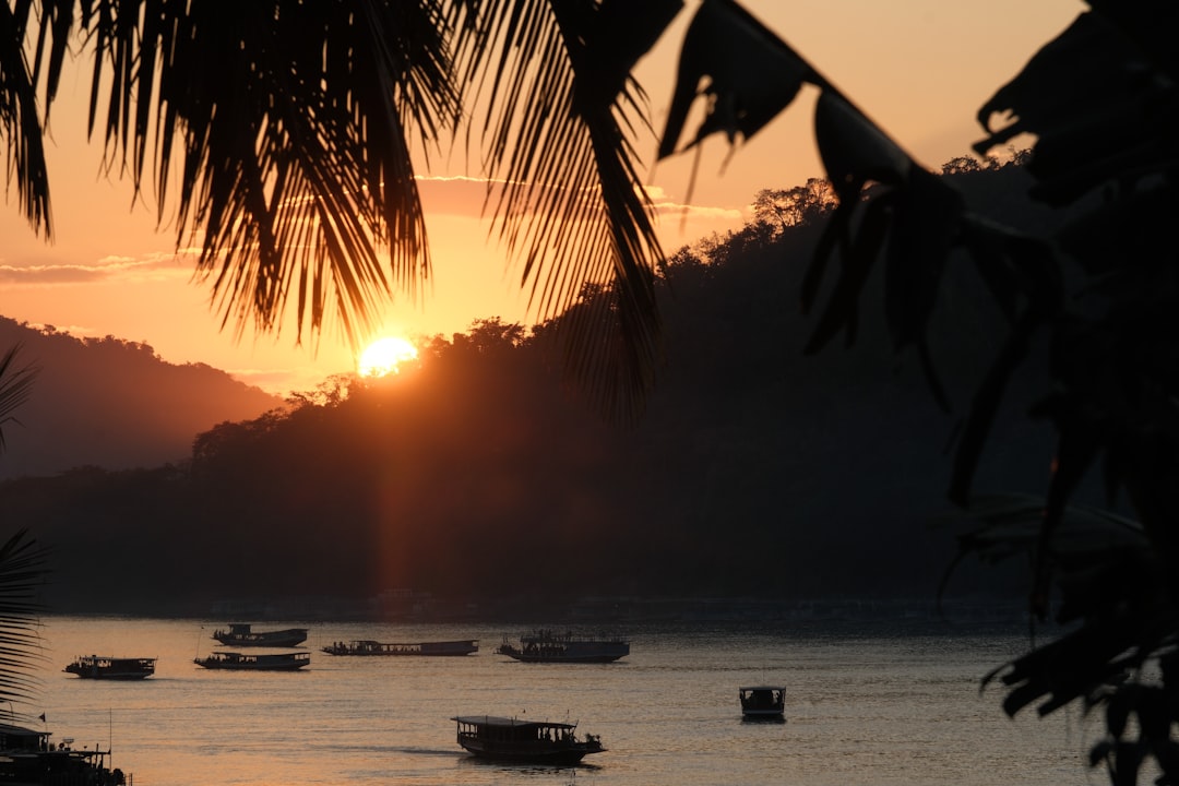 Small tour boat cruising on a river at sunset with bridges behind