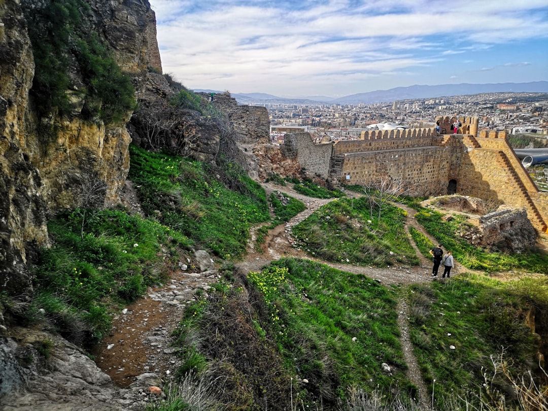 Stone walls of Narikala Fortress overlooking the rooftops of Tbilisi at sunset
