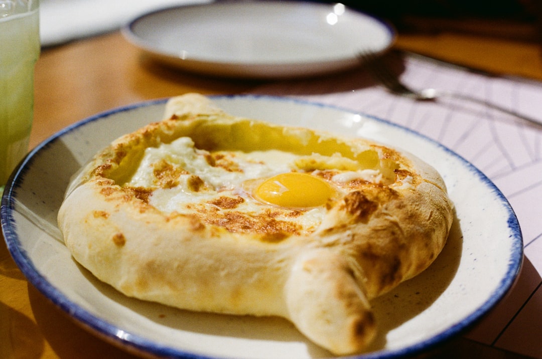 Adjarian khachapuri boat-shaped bread filled with cheese and egg on a wooden table
